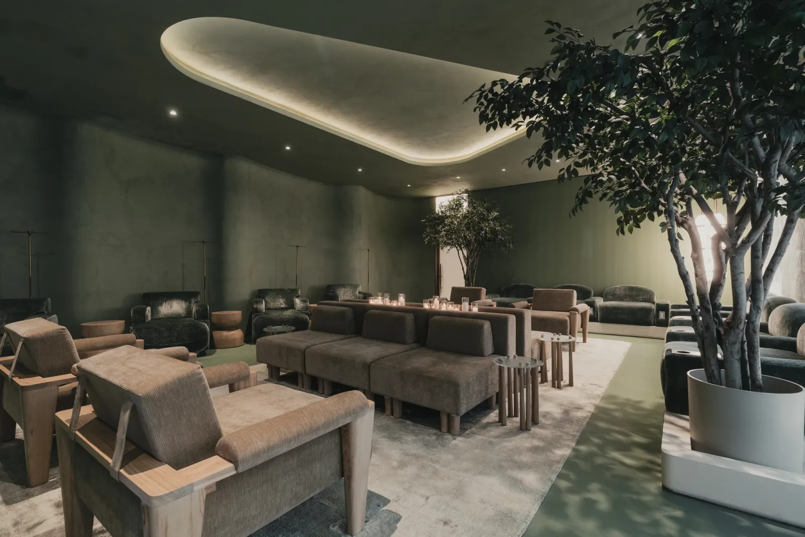 LIVV Wellness — green plaster lounge with custom upholstered seating and backlit ceiling cove